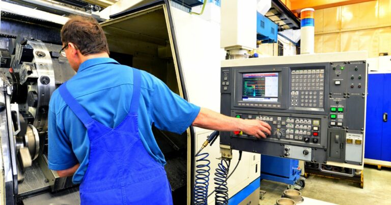 Egy gyári munkás CNC marógépet működtet a mechanikai alkatrészek gyártásához.